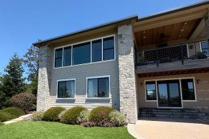 Modern two-story house with stone accents, large windows, and a manicured front yard.