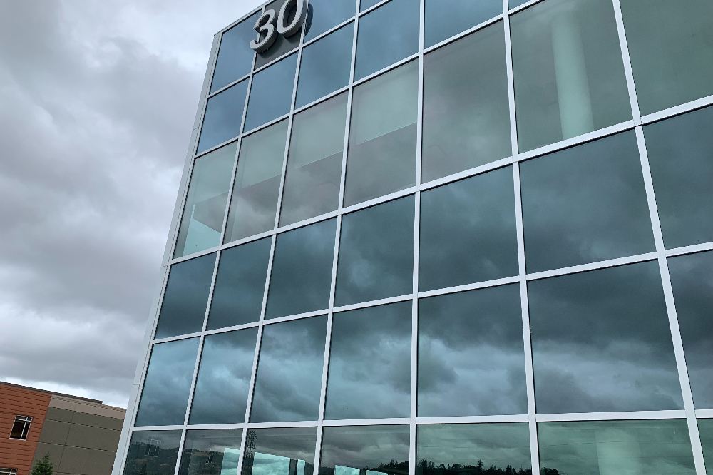 Modern glass office building with a grid of reflective windows and the number 30 at the top corner.