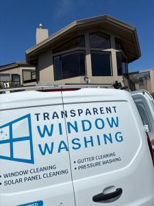 IMG_0618 - Transparent Window Washing White van with blue 'Transparent Window Washing' logo and service list parked in front of a modern house; window cleaning company advertisement visible on the side.