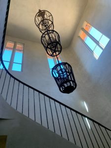 IMG_4061 - Transparent Window Washing Interior atrium with a curved black railing and hanging metal cage sculptures near tall windows.