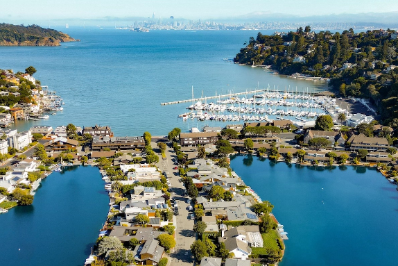 Aerial view of a waterfront residential area with a marina to the right and blue inlets flanking the houses.